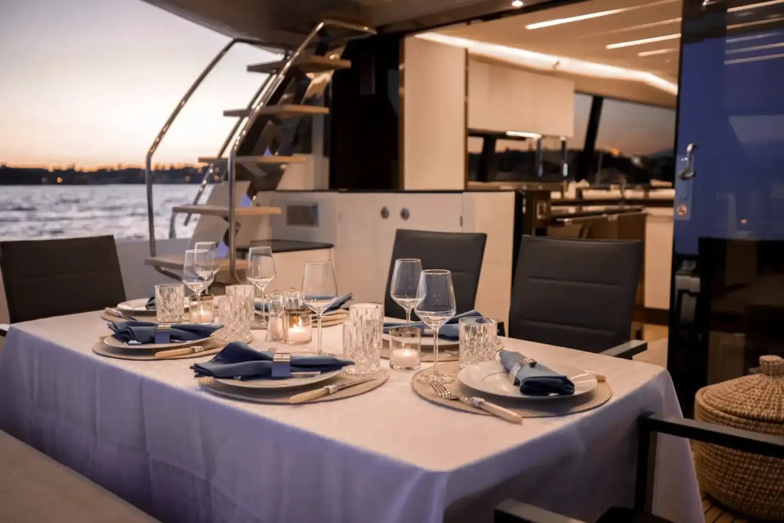 A dining table laid for dinner aboard the yacht APOLLONIA, with the marina behind