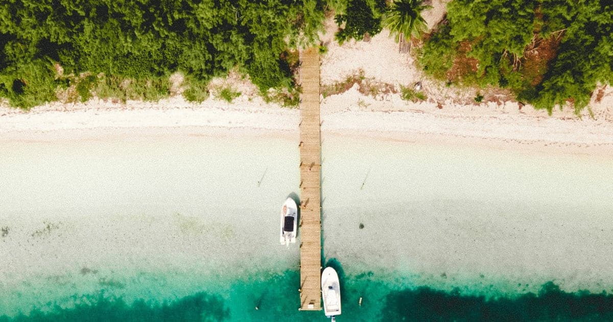 Boats at a jetty off a white beach on Manjack Cay in the Abacos